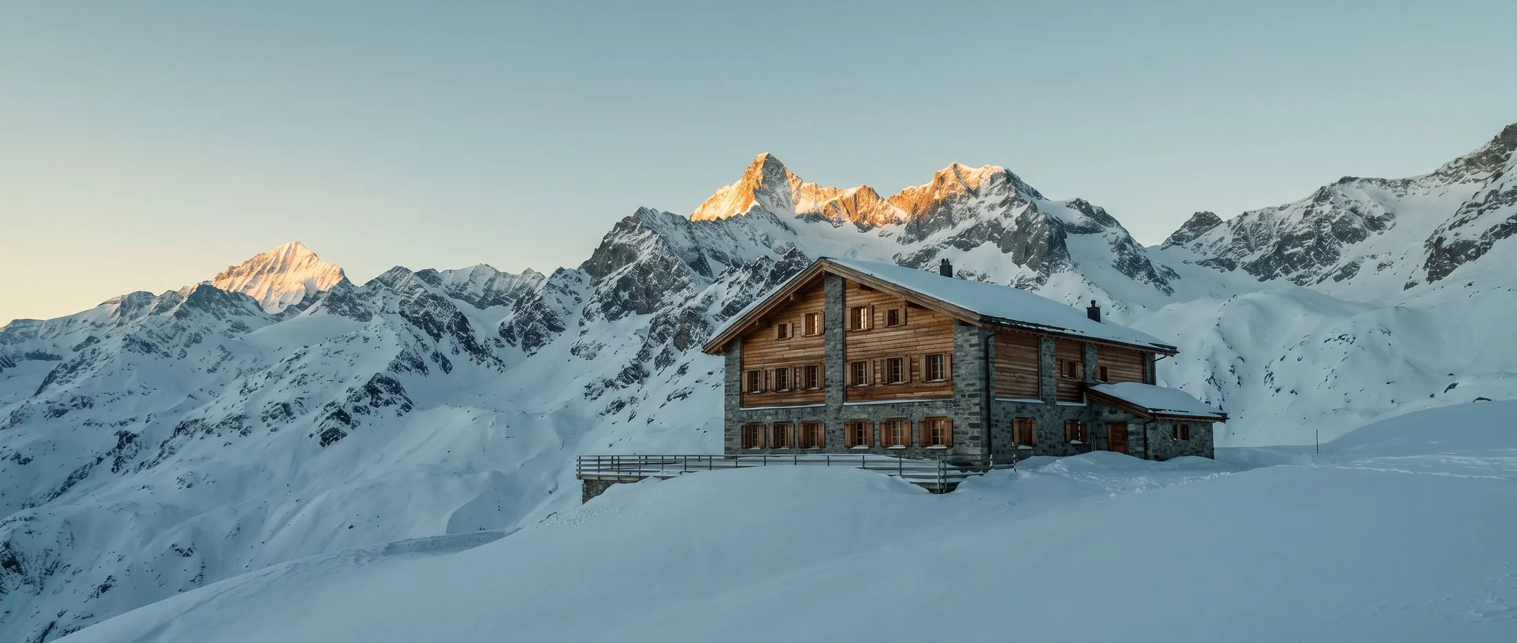 La Maison Ténaz à l’aube : ciel pâle et froid, premier soleil sur les hauts sommets, neige encore bleue à l’ombre.