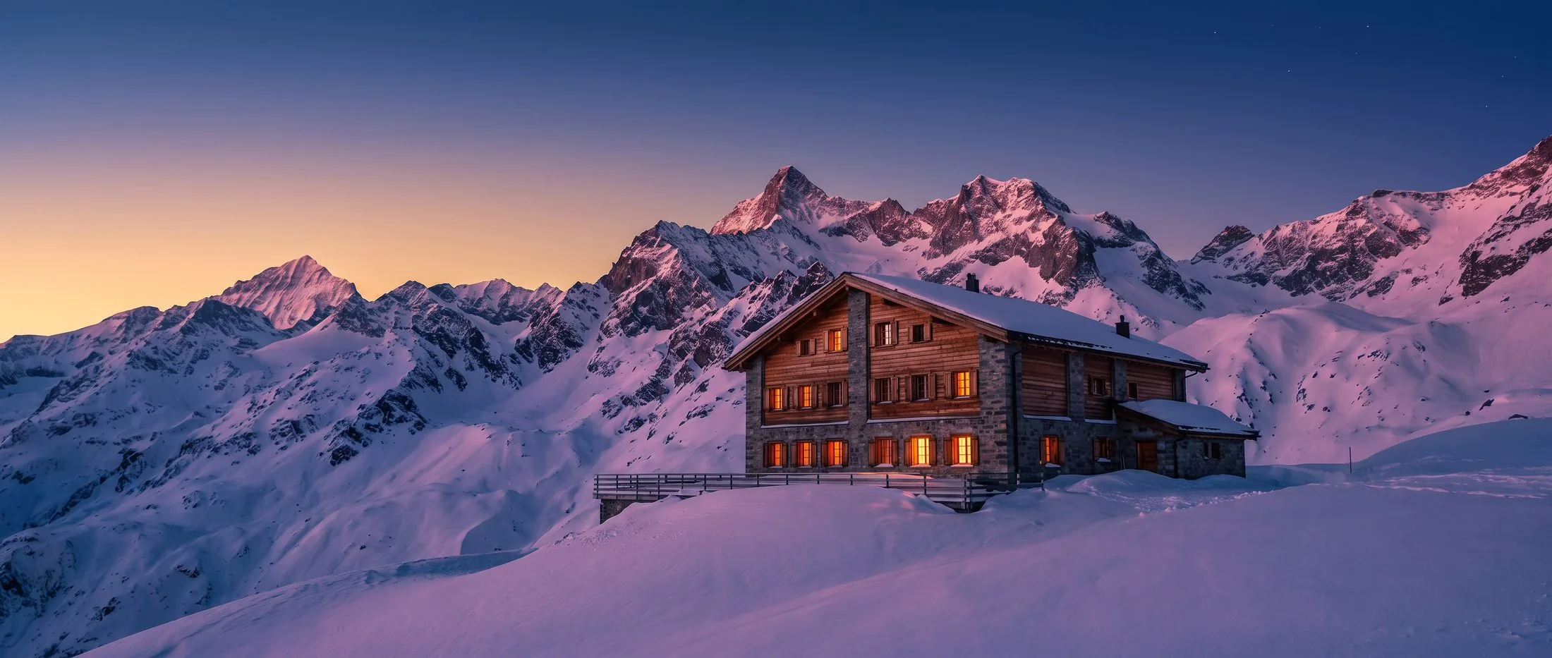 La même maison à l’alpenglow : les sommets et la neige virent au rose et au violet, le ciel passe de l’abricot à l’indigo.
