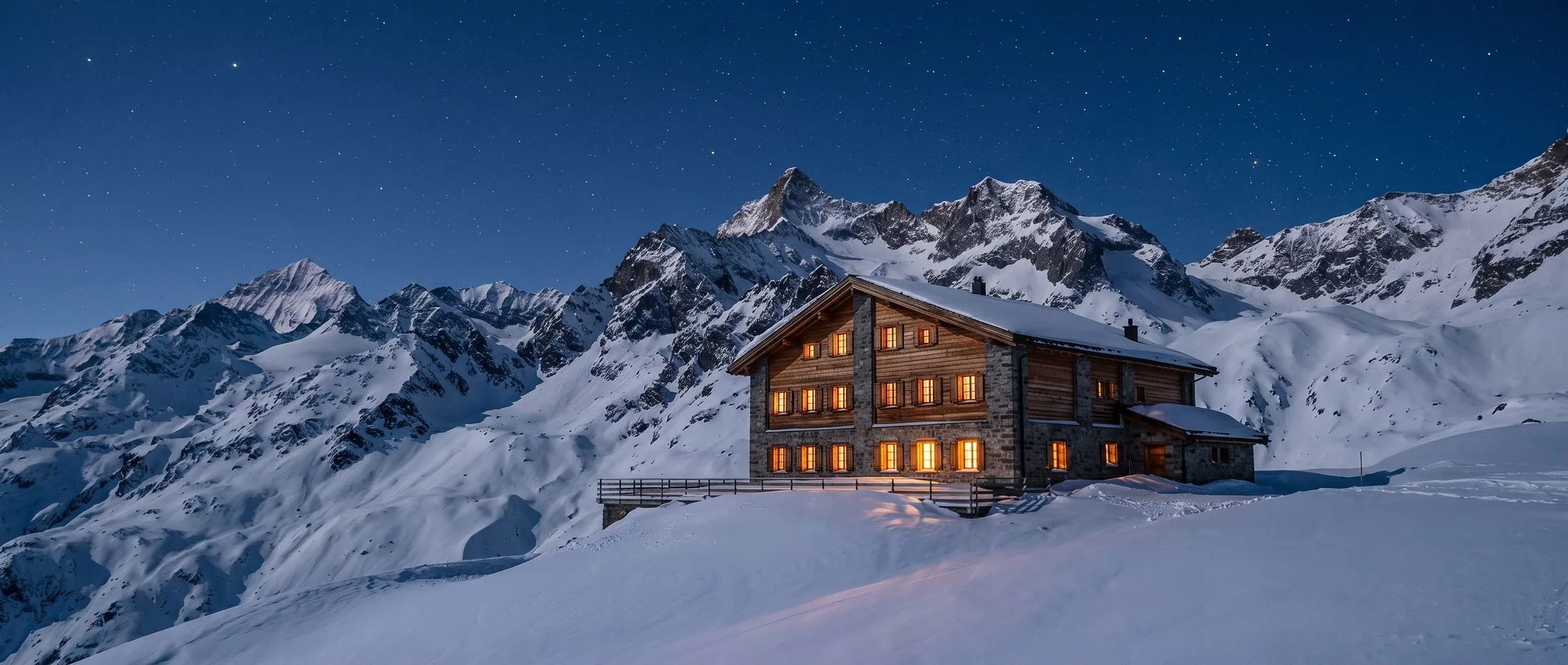 La même maison en pleine nuit : neige argentée au clair de lune, ciel étoilé, toutes les fenêtres ambrées.